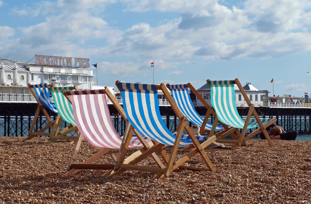 With Brighton pier in the background, the focus is on two deck chairs on Brighton beach